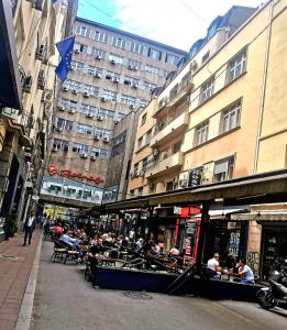 un grupo de personas sentadas en mesas en una calle de la ciudad en Dani City Center Apartment, en Belgrado