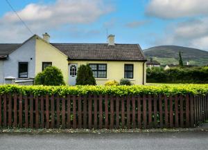 uma casa amarela com uma cerca em frente em Garden Holiday Cottage by Trident Holiday Homes em Clogheen