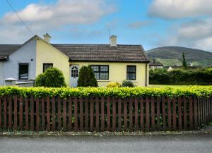 a yellow house with a fence in front of it at Garden Holiday Cottage by Trident Holiday Homes in Clogheen