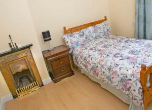 a bedroom with a bed and a dresser with a fireplace at Garden Holiday Cottage by Trident Holiday Homes in Clogheen