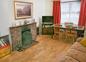 een woonkamer met een open haard en een tafel met stoelen bij Garden Holiday Cottage by Trident Holiday Homes in Clogheen