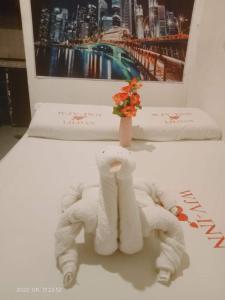 a table with two towels and a vase with flowers at WJV INN Mandaue Centro in Mandaue City