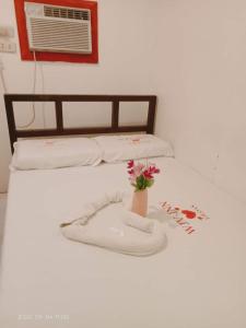 a bed with a vase with a flower on it at WJV INN Mandaue Centro in Mandaue City