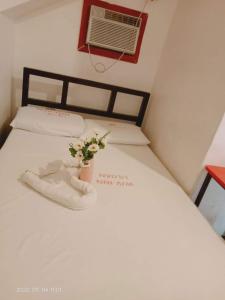 a white bed with a vase with flowers on it at WJV INN Mandaue Centro in Mandaue City