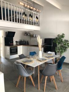 a dining room with a table and blue chairs at Maison au cœur de la La Palmyre in Les Mathes