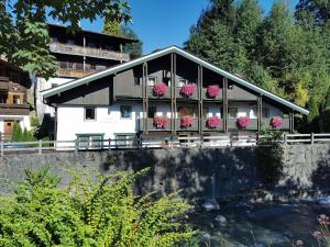 a building with flowers on the balcony next to a river at Haus am Bach in Kirchberg in Tirol