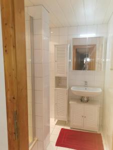 a white bathroom with a sink and a mirror at Haus am Bach in Kirchberg in Tirol