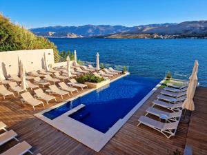 a swimming pool with chairs and the water at Hotel Plaza in Pag