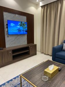 uma sala de estar com televisão e um sofá azul em دانة الفخامه للشقق الخدومة em Tabuk