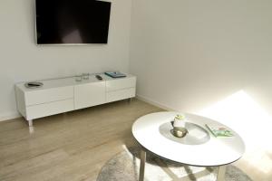 een witte woonkamer met een witte tafel en een tv bij Pilsumer Sternekieker in Krummhörn