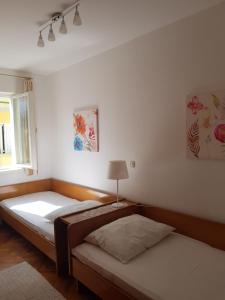 een slaapkamer met twee bedden en een raam bij Apartments Antica in Rab