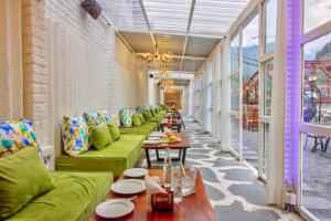 una fila de mesas y sofás verdes en una habitación en PARADISE-The Whitehouse Cafe, en Manali