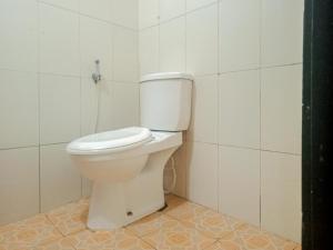 um WC branco numa casa de banho com azulejos brancos em Homestay Akik Hijau Near Panakkukang em Pampang