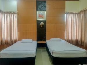 2 camas individuais num quarto com paredes de madeira em Homestay Akik Hijau Near Panakkukang em Pampang mais 26 fotografias