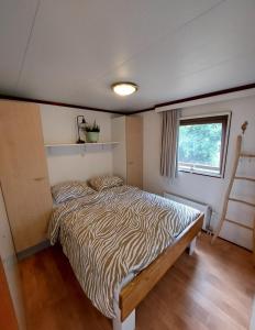 1 dormitorio con cama con estampado de cebra y ventana en Heerlijk chalet in prachtige natuur., en Doornspijk