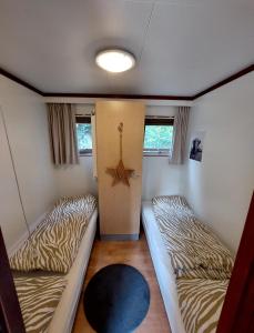 two beds in a room with two windows at Heerlijk chalet in prachtige natuur. in Doornspijk