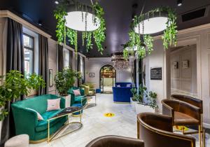 バクーにあるIvy Garden Hotel Bakuの緑の椅子と鉢植えの植物があるロビー