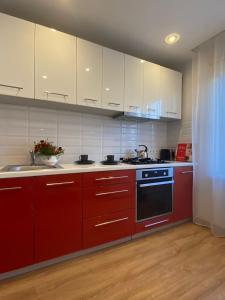 a red kitchen with white cabinets and a stove at Nameja Best view apartamenti in Jēkabpils
