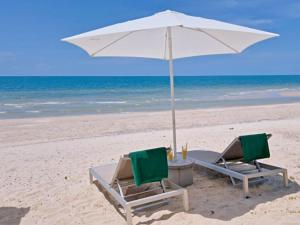 dwa krzesła i parasol na plaży w obiekcie Le Petit Saint Tropez w mieście Khanom