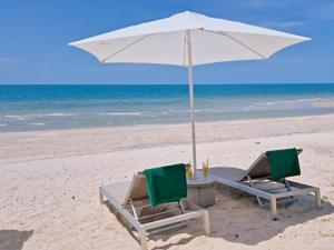 two chairs and an umbrella on a beach at Le Petit Saint Tropez in Khanom