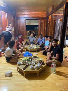 a group of people sitting around a table with food at Tuệ Nhi Homestay Ngườm Ngao Bản Giốc in Cao Bằng