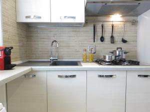 a kitchen with white cabinets and a sink at Pasubio Apartment in Bologna