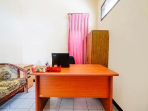 a wooden desk with a laptop on top of it at SPOT ON 91392 Pondok Basari in Bandung