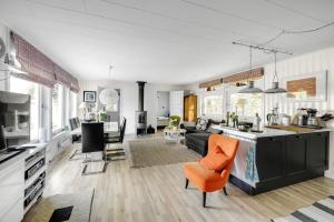cocina abierta y sala de estar con silla naranja en Nice holiday home in Julita, Katrineholm en Julita