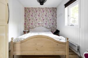 1 dormitorio con cama de madera y papel pintado con motivos florales en Nice holiday home in Julita, Katrineholm, en Julita