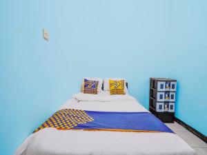 a bed in a room with a blue wall at SPOT ON 91392 Pondok Basari in Bandung