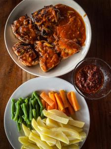dois pratos de alimentos com carne e legumes sobre uma mesa em Floating Paradise em Karimunjawa