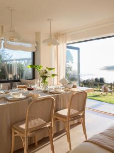 comedor con mesa y sillas y ventana grande en Espectacular Villa con acceso privado a la playa de Oyambre, en San Vicente de la Barquera