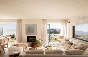 una sala de estar con un gran sofá blanco y grandes ventanas en Espectacular Villa con acceso privado a la playa de Oyambre, en San Vicente de la Barquera