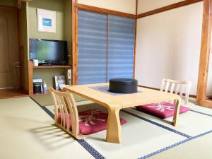 mesa y sillas en una habitación con TV en Shinyu Onsen Kurikomaso en Kurihara