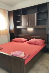 a large bed with red sheets and red pillows at Apartments Ćurić in Trogir