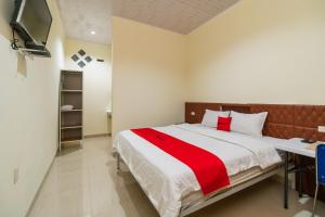 a bedroom with a bed with a red and white blanket at RedDoorz @ Aldos Villa Silangit in Siborongborong
