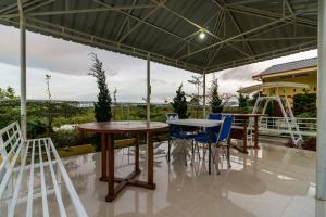 a patio with two tables and chairs under a canopy at RedDoorz @ Aldos Villa Silangit in Siborongborong