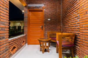 a patio with two chairs and a table in front of a brick wall at RedDoorz @ Aldos Villa Silangit in Siborongborong