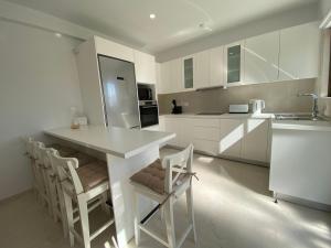 a kitchen with white cabinets and a table and chairs at Phaedrus Living: City View Luxury Flat Androcleous in Paphos City