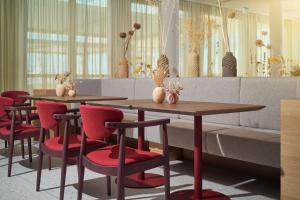 two tables and red chairs in a room at Hotel Ambasador in Split