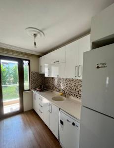 a kitchen with white cabinets and a sink and a refrigerator at Halic Apart Hotel in Yalova