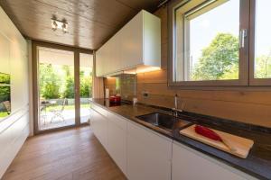 una cocina con armarios blancos, fregadero y ventanas en Primula, en Wildhaus