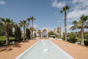 une piscine en face d'une maison avec des palmiers dans l'établissement The Residence Tunis, à Gammarth