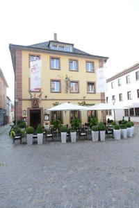 a large building with tables and chairs in a courtyard at Land-gut Hotel zum Löwen Garni in Marktheidenfeld