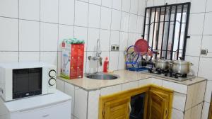 een kleine keuken met een wastafel en een magnetron bij MEJOM HOTEL & APARTMENTS Douala - Ndobo Bonaberi in Douala