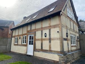 um velho celeiro com uma porta branca e janelas em Alexander Park B&B em Ledbury