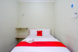 a white bed with a red pillow on it at RedDoorz Syariah near Gerbang Tol Krapyak 2 Semarang in Kalibanteng-kidul
