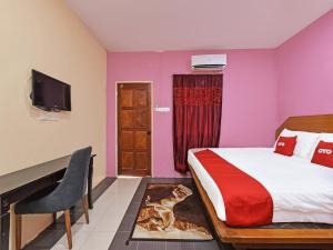 a bedroom with a bed and a desk and a tv at OYO 90561 Awan Biru Motel in Pantai Cenang