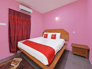 a bedroom with a large bed with pink walls at OYO 90561 Awan Biru Motel in Pantai Cenang