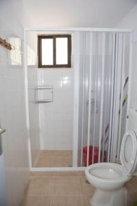 a white bathroom with a shower and a toilet at Vasileiou Apartments in Kamena Vourla